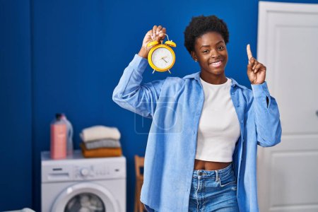 Photo for African american woman waiting for laundry surprised with an idea or question pointing finger with happy face, number one - Royalty Free Image
