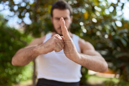 Photo for Young hispanic man karate fighter doing combat salute at park - Royalty Free Image