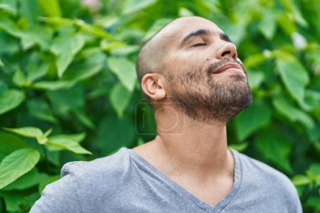 Photo for Young latin man breathing with closed eyes at park - Royalty Free Image