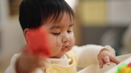 Foto de Adorable bebé hispano jugando con bloques de construcción sentados en la mesa en el jardín de infantes - Imagen libre de derechos