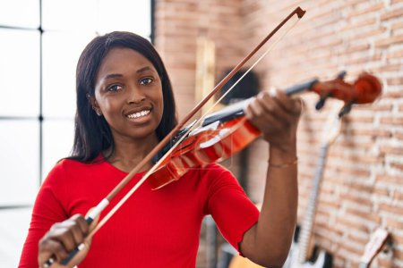 Photo for Young african american woman musician playing violin at music studio - Royalty Free Image