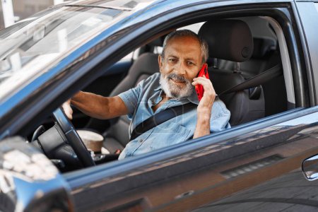 Téléchargez les photos : Senior homme aux cheveux gris parler sur smartphone assis sur la voiture à la rue - en image libre de droit
