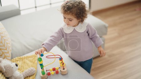 Foto de Adorable chica hispana jugando con juguete de pie en casa - Imagen libre de derechos