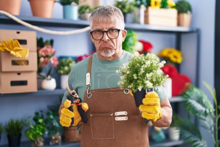 Photo for Hispanic man with grey hair working at florist shop depressed and worry for distress, crying angry and afraid. sad expression. - Royalty Free Image