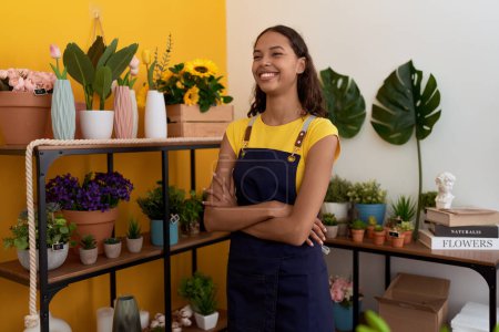 Téléchargez les photos : Jeune afro-américaine fleuriste souriant confiant debout avec les bras croisés geste à la boutique de fleurs - en image libre de droit