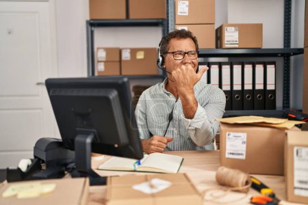 Foto de Senior man working at small business ecommerce wearing headset pointing thumb up to the side smiling happy with open mouth - Imagen libre de derechos