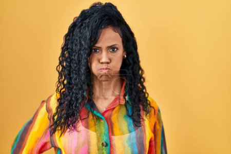 Téléchargez les photos : Middle age hispanic woman standing over yellow background puffing cheeks with funny face. mouth inflated with air, crazy expression. - en image libre de droit