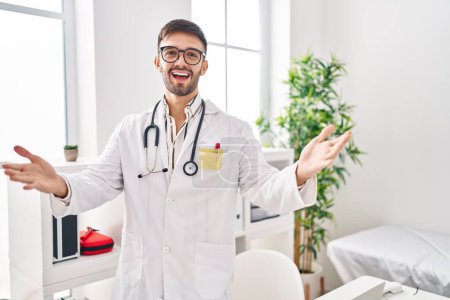 Téléchargez les photos : Hispanic man wearing doctor uniform and stethoscope looking at the camera smiling with open arms for hug. cheerful expression embracing happiness. - en image libre de droit