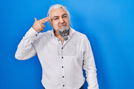 Téléchargez les photos : Middle age man with grey hair standing over blue background shooting and killing oneself pointing hand and fingers to head like gun, suicide gesture. - en image libre de droit