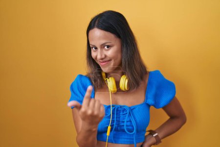 Téléchargez les photos : Hispanic young woman standing over yellow background beckoning come here gesture with hand inviting welcoming happy and smiling - en image libre de droit