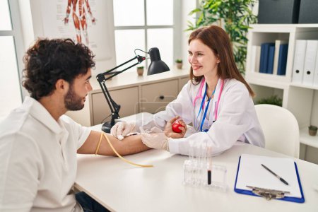 Photo for Man and woman wearing doctor uniform having blood analysis at clinic - Royalty Free Image