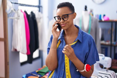 Téléchargez les photos : African american woman tailor smiling confident talking on smartphone at tailor shop - en image libre de droit