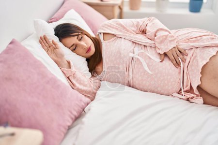 Téléchargez les photos : Jeune femme enceinte couchée sur le lit dormant dans la chambre - en image libre de droit