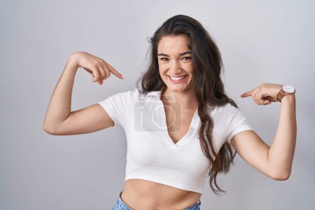 Photo for Young teenager girl standing over white background looking confident with smile on face, pointing oneself with fingers proud and happy. - Royalty Free Image