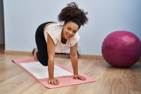 Photo for Young african american woman smiling confident stretching at sport center - Royalty Free Image