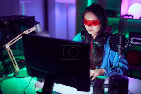 Téléchargez les photos : Jeune femme chinoise streamer jouer à un jeu vidéo en utilisant des lunettes de réalité virtuelle à la salle de jeux - en image libre de droit