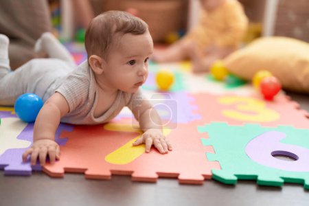 Photo for Adorable toddler lying on floor playing at kindergarten - Royalty Free Image
