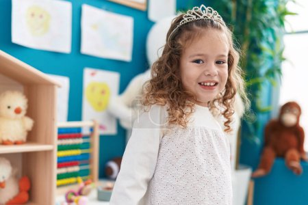 Photo for Adorable blonde toddler smiling confident wearing princess crown at kindergarten - Royalty Free Image
