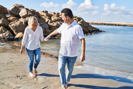 Téléchargez les photos : Middle age man and woman couple smiling confident walking at seaside - en image libre de droit