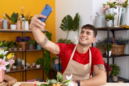 Foto de Young hispanic man florist make selfie by smartphone at flower shop - Imagen libre de derechos