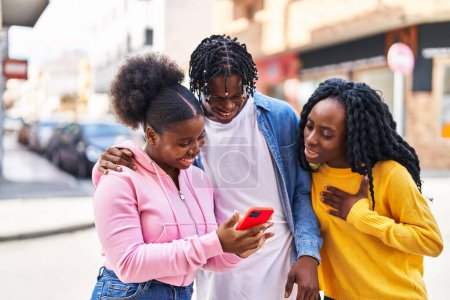 Téléchargez les photos : Des amis afro-américains debout ensemble en utilisant un smartphone dans la rue - en image libre de droit