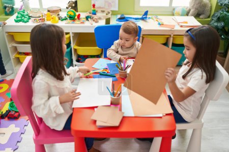 Foto de Grupo de niños estudiantes de preescolar sentados en el dibujo de la mesa y hacer manualidades en el jardín de infantes - Imagen libre de derechos