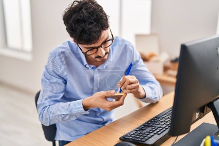 Téléchargez les photos : Young caucasian man business worker using computer writing on reminder paper at office - en image libre de droit