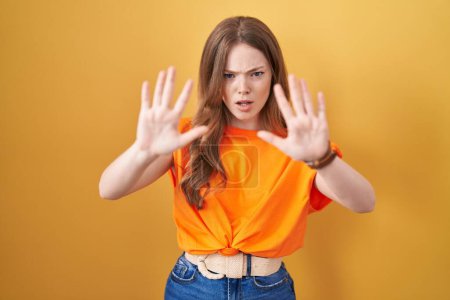 Téléchargez les photos : Caucasian woman standing over yellow background doing stop gesture with hands palms, angry and frustration expression - en image libre de droit