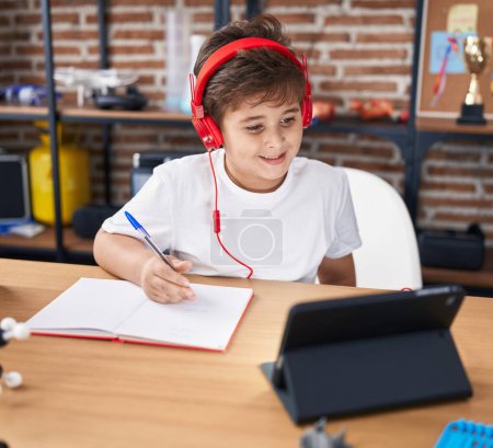 Téléchargez les photos : Adorable élève hispanique garçon en utilisant touchpad écriture sur ordinateur portable en classe - en image libre de droit