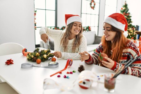 Foto de Mujer pareja haciendo decoración de Navidad hecha a mano sentado en la mesa en casa - Imagen libre de derechos