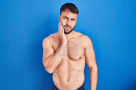 Photo for Handsome hispanic man standing shirtless touching mouth with hand with painful expression because of toothache or dental illness on teeth. dentist - Royalty Free Image
