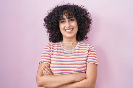 Téléchargez les photos : Young middle east woman standing over pink background happy face smiling with crossed arms looking at the camera. positive person. - en image libre de droit