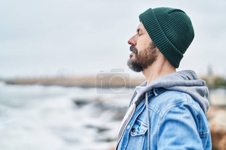 Téléchargez les photos : Jeune homme chauve respirant les yeux fermés au bord de la mer - en image libre de droit