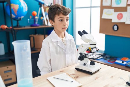 Foto de Adorable hispanic boy student standing with relaxed expression at laboratory classroom - Imagen libre de derechos