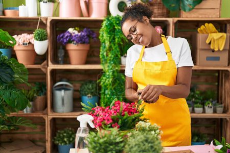 Photo for African american woman florist cutting plants at flower shop - Royalty Free Image