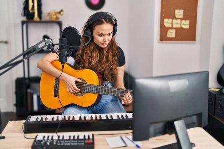 Foto de Joven hermosa mujer hispana músico tocando la guitarra clásica en el estudio de música - Imagen libre de derechos