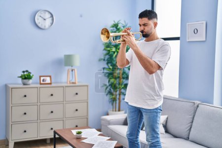 Téléchargez les photos : Jeune homme arabe musicien jouer de la trompette debout à la maison - en image libre de droit