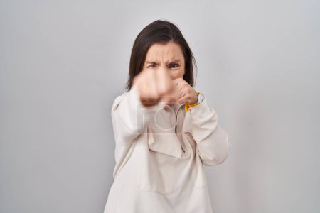 Photo for Middle age hispanic woman standing over isolated background punching fist to fight, aggressive and angry attack, threat and violence - Royalty Free Image