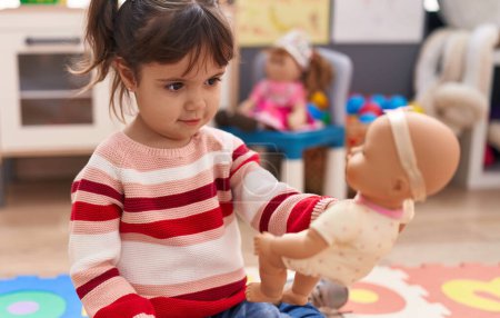 Foto de Adorable chica hispana jugando con la muñeca de pie en el jardín de infantes - Imagen libre de derechos