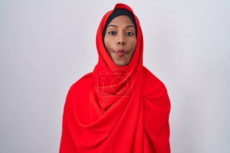 Téléchargez les photos : Jeune femme arabe portant l'écharpe traditionnelle islamique hijab faire visage de poisson avec des lèvres, geste fou et comique. expression drôle. - en image libre de droit