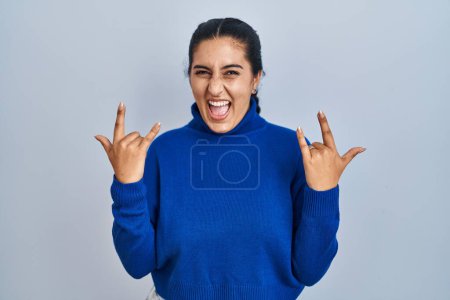 Photo for Young hispanic woman standing over isolated background shouting with crazy expression doing rock symbol with hands up. music star. heavy music concept. - Royalty Free Image
