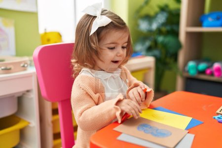 Photo for Adorable blonde toddler preschool student sitting on table drawing on paper at kindergarten - Royalty Free Image