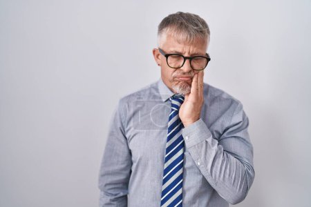 Photo for Hispanic business man with grey hair wearing glasses touching mouth with hand with painful expression because of toothache or dental illness on teeth. dentist - Royalty Free Image