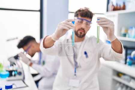 Photo for Young couple wearing scientist uniform holding test tubes at laboratory - Royalty Free Image