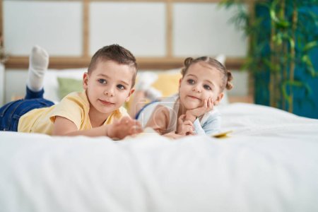 Foto de Dos niños leyendo un libro de cuentos acostados en la cama en el dormitorio - Imagen libre de derechos