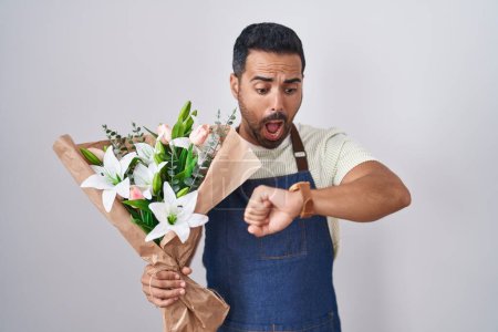 Photo for Hispanic man with beard working as florist looking at the watch time worried, afraid of getting late - Royalty Free Image