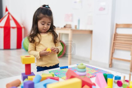 Photo for Adorable hispanic girl playing with construction blocks standing at kindergarten - Royalty Free Image
