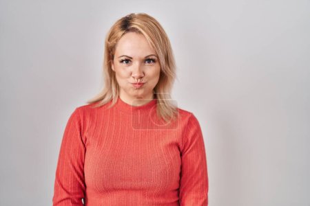 Photo for Blonde woman standing over isolated background puffing cheeks with funny face. mouth inflated with air, crazy expression. - Royalty Free Image