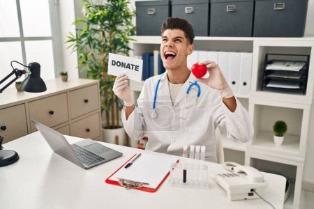 Photo for Young hispanic doctor man supporting organs donations angry and mad screaming frustrated and furious, shouting with anger looking up. - Royalty Free Image