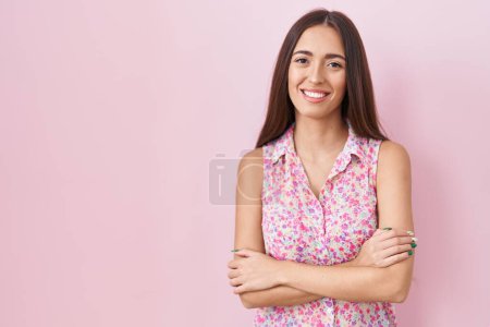 Téléchargez les photos : Jeune femme hispanique aux cheveux longs debout sur fond rose heureux visage souriant avec les bras croisés regardant la caméra. personne positive. - en image libre de droit